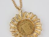 a gold necklace with a coin in the middle of it