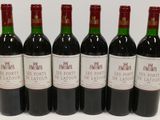 six bottles of red wine are lined up on a table