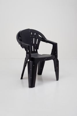 une chaise en plastique noire posée sur un sol blanc