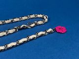 a close up of a chain with a pink flower on it