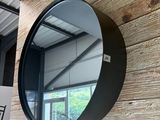 un miroir rond accroché à un mur en bois, à côté d'un panneau