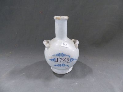 un vase blanc orné d'une inscription bleue, posé sur une table
