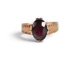 a close up of a gold ring with a red stone