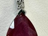 un gros plan d'un pendentif en rubis et diamants sur fond blanc