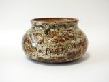 un vase brun et blanc posé sur une surface blanche