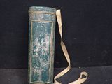 a green tin with a strap on it sitting on a black surface