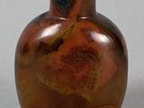 a brown vase with a green lid sitting on a table
