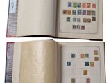 two pages of a book with stamps are open on a white surface