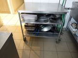 un chariot de cuisine en acier inoxydable sur lequel sont posés des casseroles et des poêles