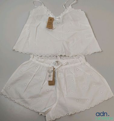 deux vêtements blancs posés sur une table, avec une étiquette dessus