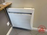 un radiateur blanc posé à même le sol, près d'un mur