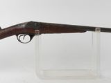 un fusil posé sur un socle transparent, devant un fond blanc