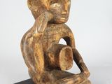 an image of a wooden sculpture of a man holding a pot