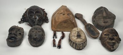 ensemble de masques africains posés sur une surface blanche, sur fond blanc