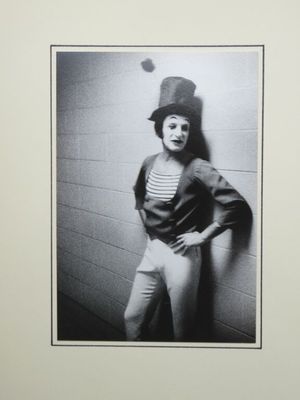 black and white photograph of a woman leaning against a wall wearing a top hat