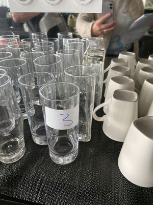many glasses and cups on a table with a person in the background