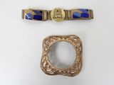 two pieces of gold and blue jewelry on a white surface
