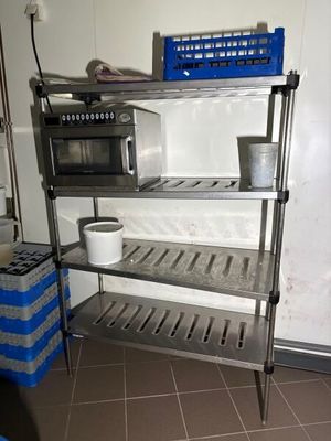 a metal shelf with a microwave on top of it