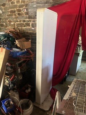 a refrigerator in a room with a red curtain on the wall