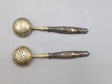 pair of silver spoons with handles and handles on a white surface