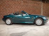 a picture of a green sports car parked in front of a brick wall