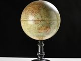 un vieux globe terrestre posé sur un socle, avec un fond noir
