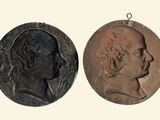 two bronze medallions of a man and a woman on a white background