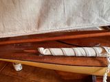 a wooden boat with a sail and a knife on it