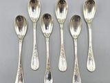six cuillères en argent ornées de motifs élaborés, posées sur une table