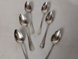 six silver spoons are arranged in a circle on a white surface