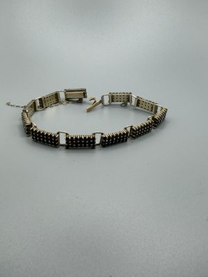 un bracelet noir et argenté orné de perles carrées sur fond blanc