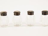 three small glass salt and pepper shakers lined up on a white surface