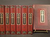 six red books are lined up on a black surface