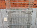 a metal rack with three baskets on it in front of a brick wall