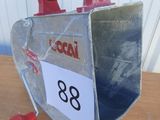 une petite boîte en métal avec une poignée rouge posée sur une table en bois