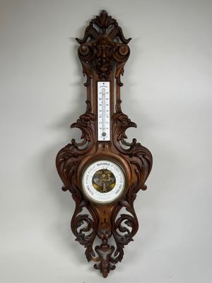une horloge en bois accrochée au mur, sur laquelle est fixé un thermomètre