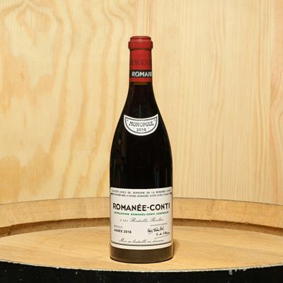 a bottle of wine sitting on top of a wooden barrel