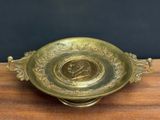 brass plate with a picture of a man on it on a wooden table