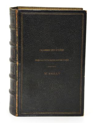 un livre noir orné de lettres dorées, posé sur une surface blanche