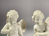 pair of white statues of cherenshes with wings on a gray background