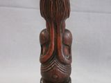 an old wooden figurine of a woman sitting on a stool