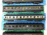 Quatre trains miniatures sont alignés les uns à côté des autres sur une surface blanche