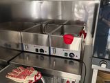 plan de travail en acier inoxydable dans une cuisine professionnelle équipée d'un four et d'un lave-vaisselle