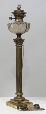 une lampe ancienne en laiton surmontée d'un abat-jour en verre