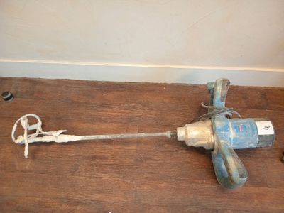 a drill on the floor next to a piece of wood