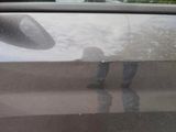 a reflection of a person standing in a car door