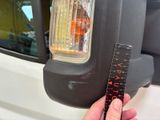 a person holding a measuring tape next to a car ' s tail light