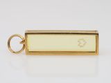 a close up of a gold plated keychain with a white enamel tag on it