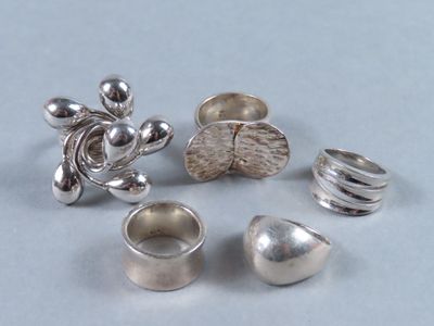 Plusieurs bagues en argent sont posées sur une table.