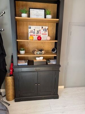 a bookcase with a coat rack and a chair in the corner
